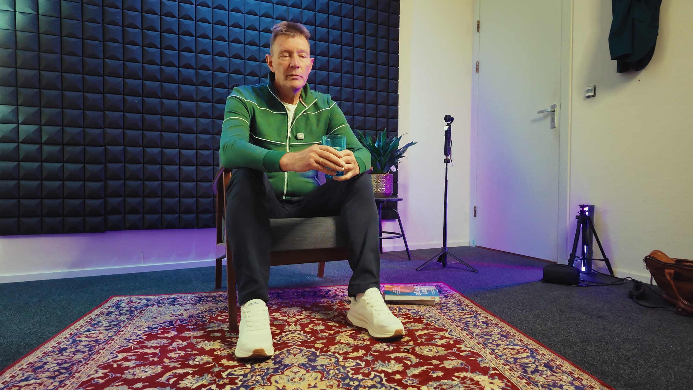 De set van het interview van opzij: Cees in zijn stoel, een microfoonstandaard en een staande lamp