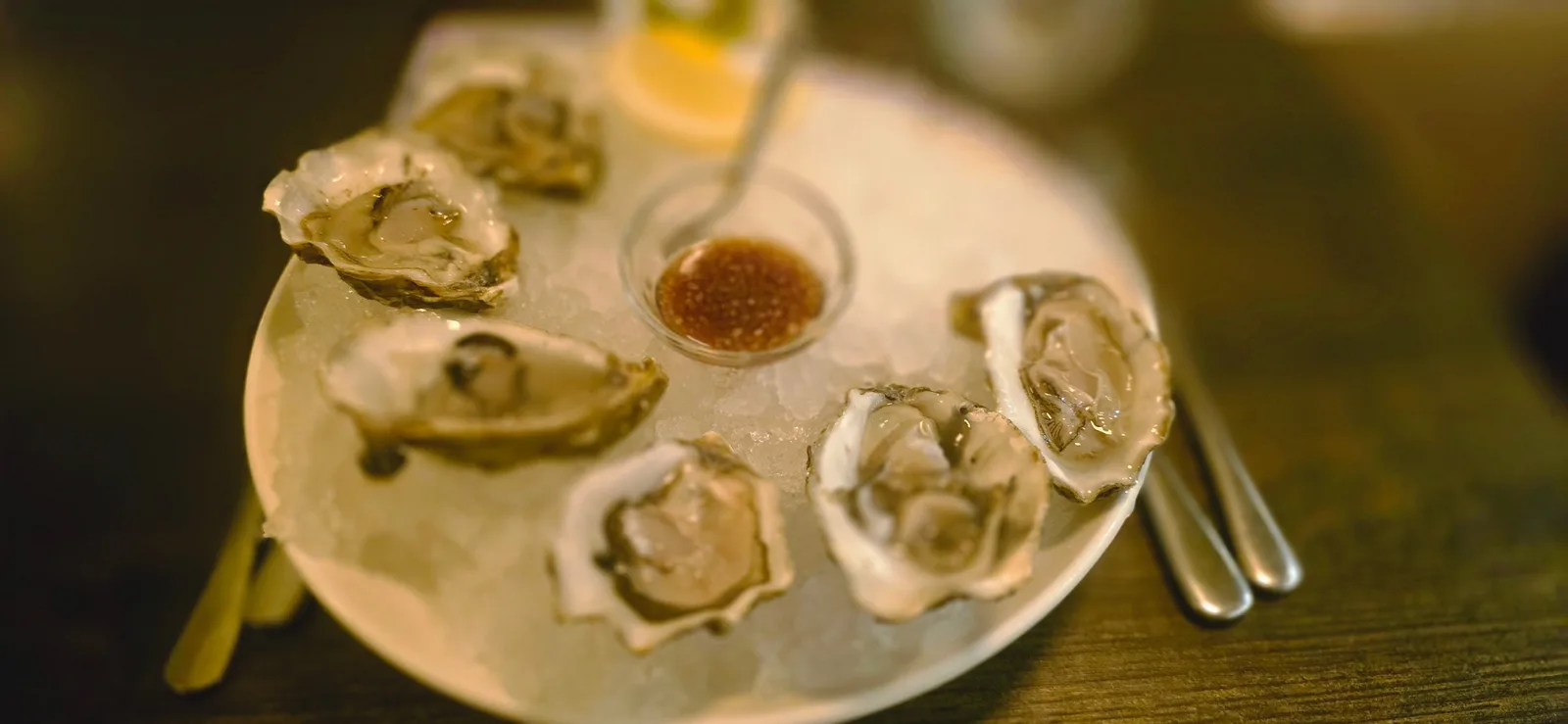 Zes oesters op ijs met een schaaltje vinaigrette