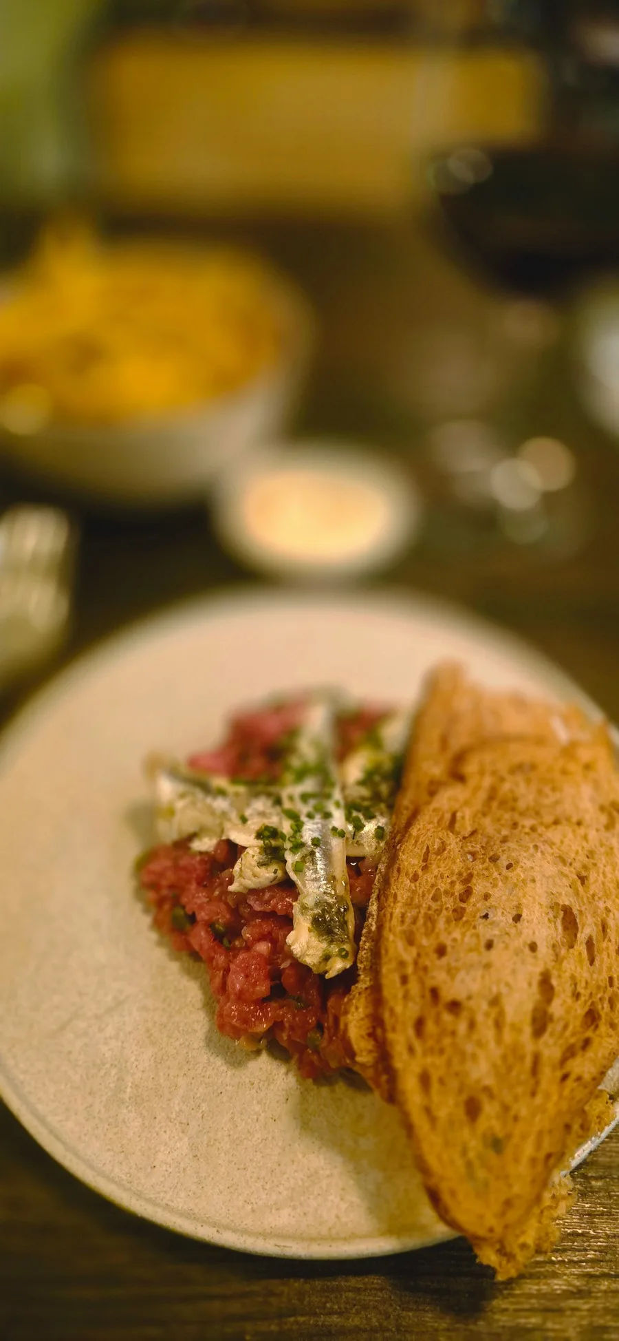 Steak tartaar met ansjovis en geroosterd brood, friet op de achtergrond