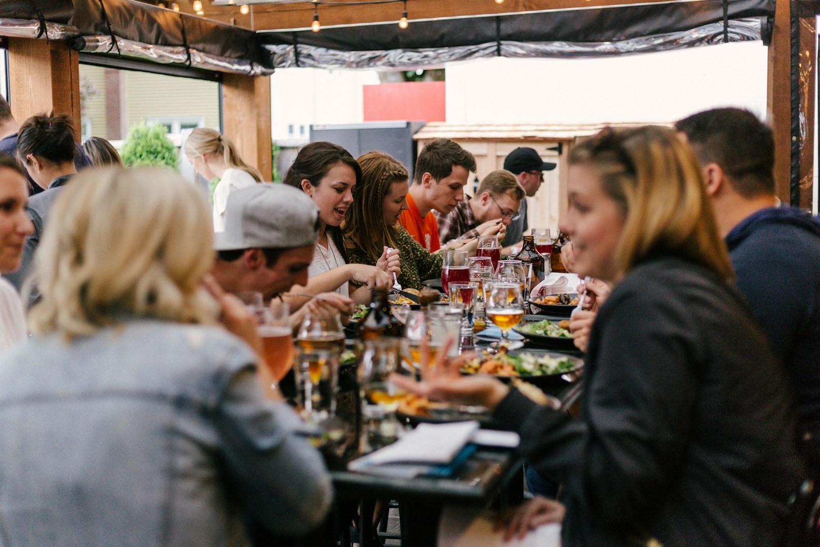 Een lange tafel vol mensen die met elkaar praten en lachen tijdens het eten