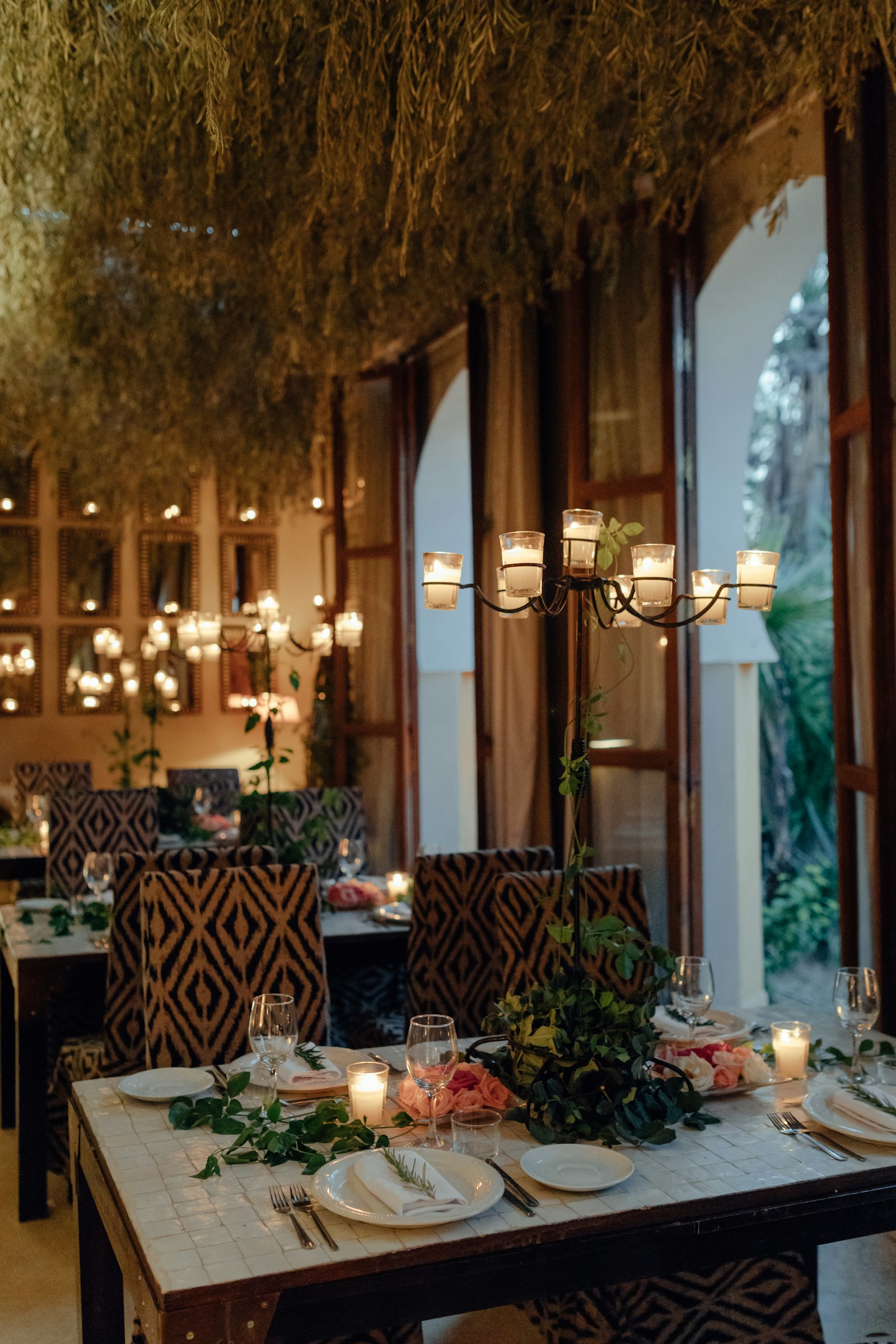 Een warm verlicht restaurant met kroonluchters en hoge ramen