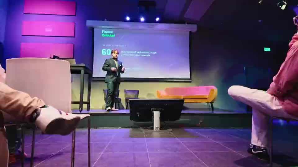 Een spreker op het podium bij Finance Unlocked, gezien vanuit de zaal