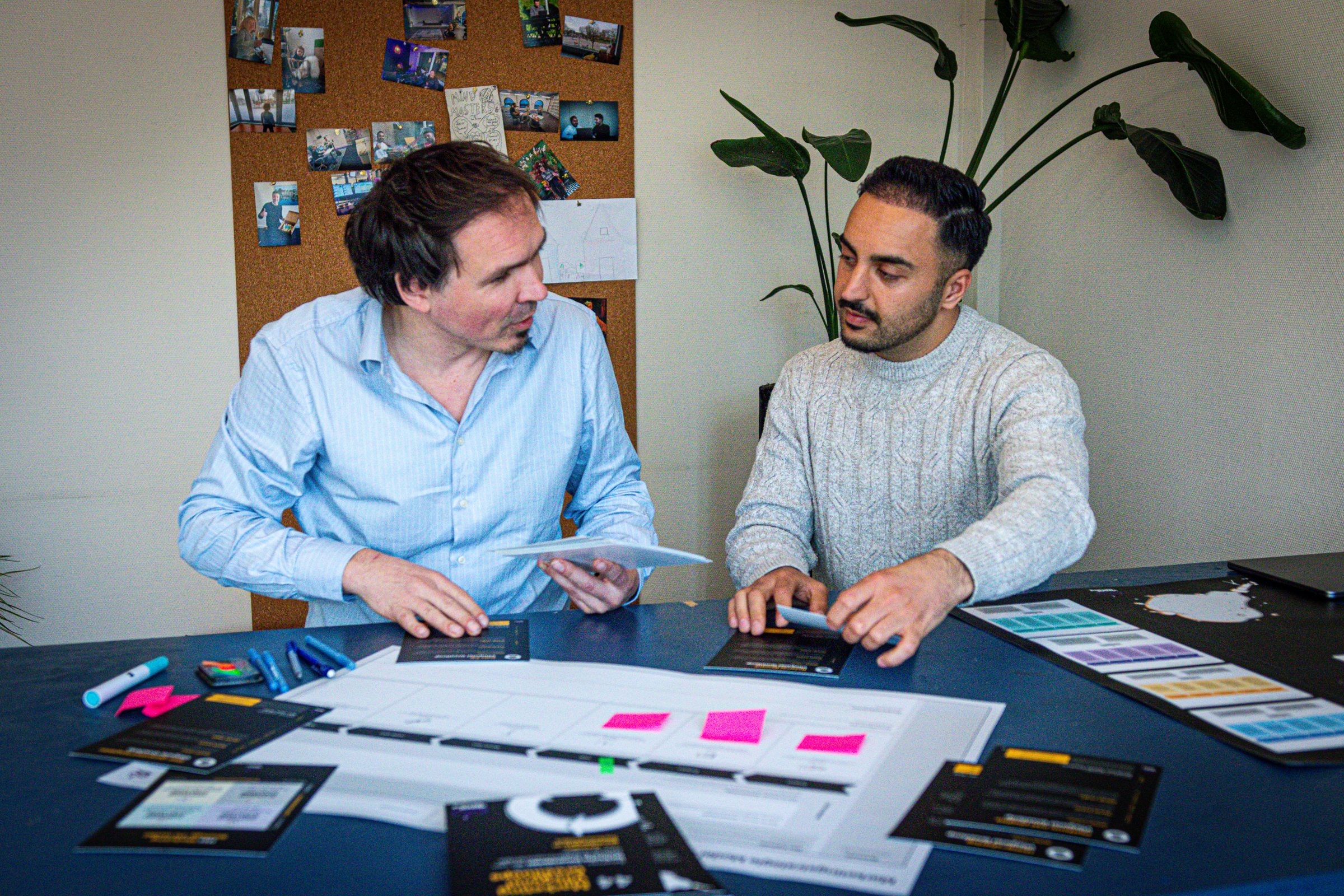 Twee mensen werken aan tafel aan een strategie met kaarten en post-its