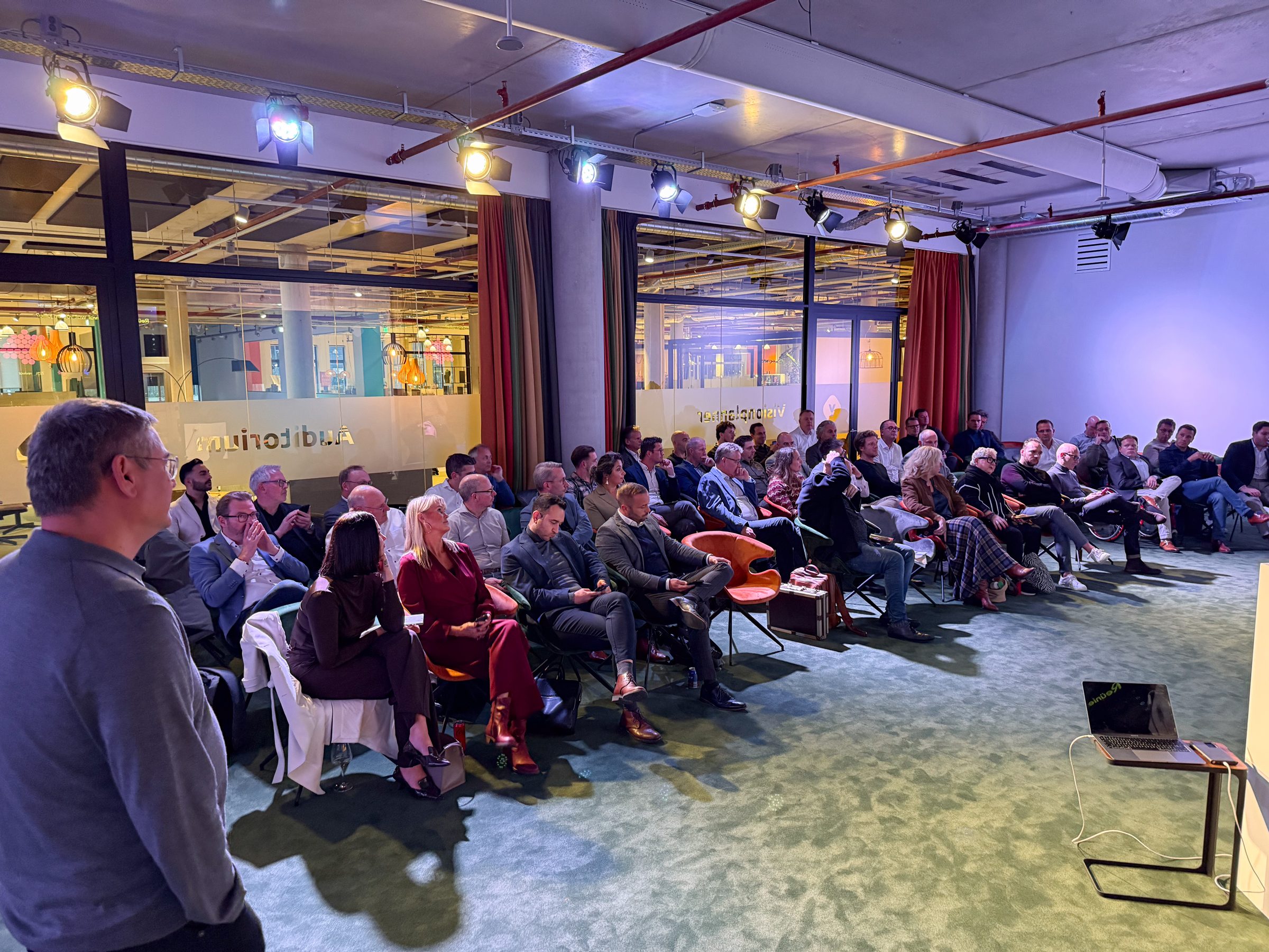 Een volle zaal luistert naar een spreker